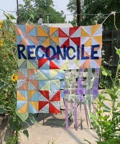 Quilt with the word Reconcile spelled out in blue fabric.