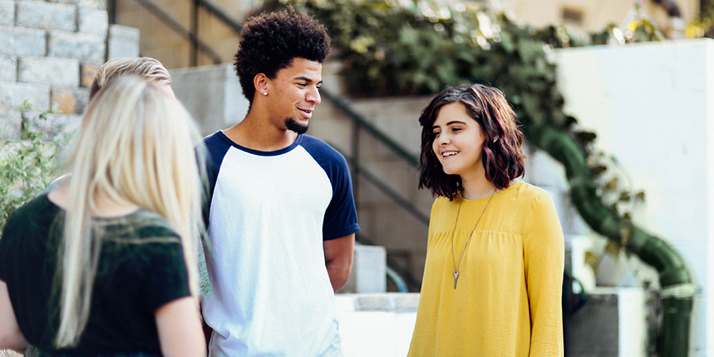 Three students talking outside of a building